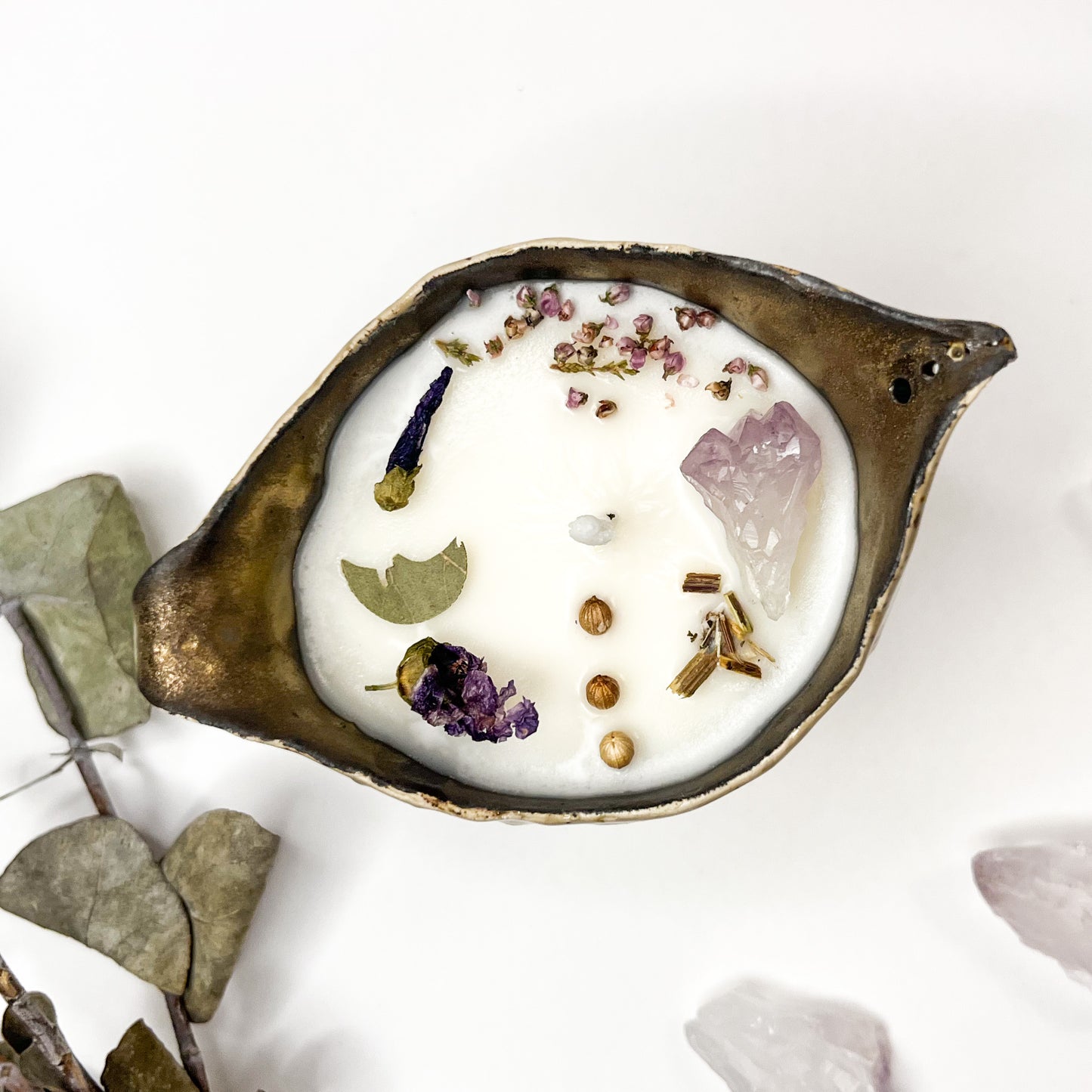 vela de cera de soja con elementos mágicos envasada en un caldero color ocre